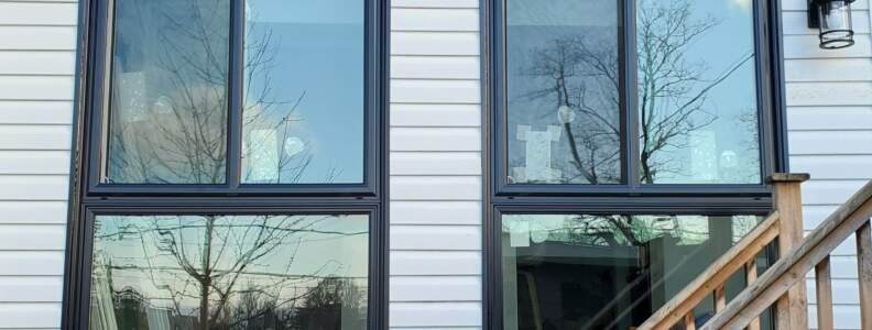 Two black-framed window combinations with white siding and matching exterior trim