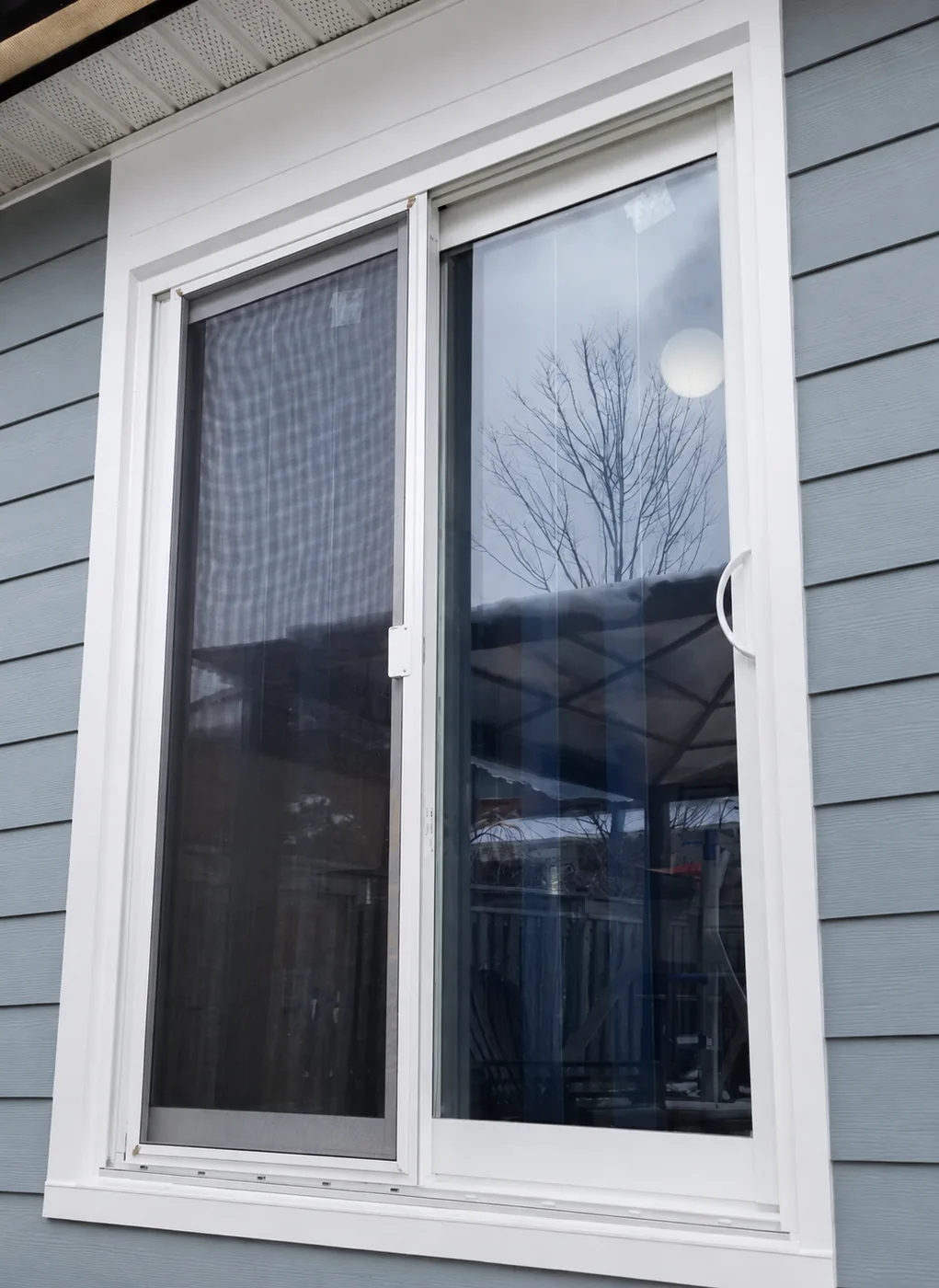 White sliding patio door installed with premium blue-grey siding
